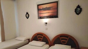 A hotel room with two single beds, a framed picture on the wall, and a small table.