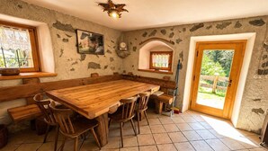 A rustic dining room with a large wooden table, benches, and chairs. - Chalet Maso Salam (Bocenago)