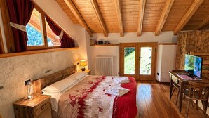 A bedroom with a wooden ceiling, a bed with a red and white bedspread, a wooden nightstand, a wooden chair, and a desk with a laptop. - Chalet Maso Salam (Bocenago)