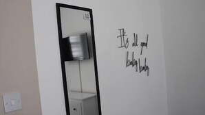 Une salle de bain avec un miroir, un luminaire fixé au mur et une citation inspirante.