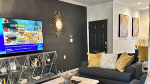 Una sala de estar moderna con un sofá gris oscuro, una mesita de centro y un televisor en la pared.