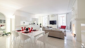 A modern living room with a dining area, a sofa, and a television. - Luxury Apartment BY Massena Square (Nice)