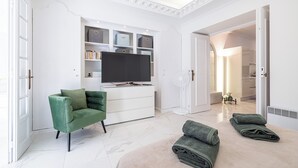 A modern living room with a green armchair, a flat-screen TV, and a white entertainment unit. - Luxury Apartment BY Massena Square (Nice)