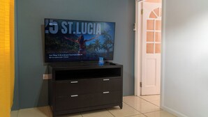 Una televisione scura su un mobile, appoggiata a una parete, mostra una guida turistica di Santa Lucia.