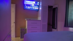 Una camera da letto con un letto, una televisione a parete, un armadio e un carrello per la biancheria.