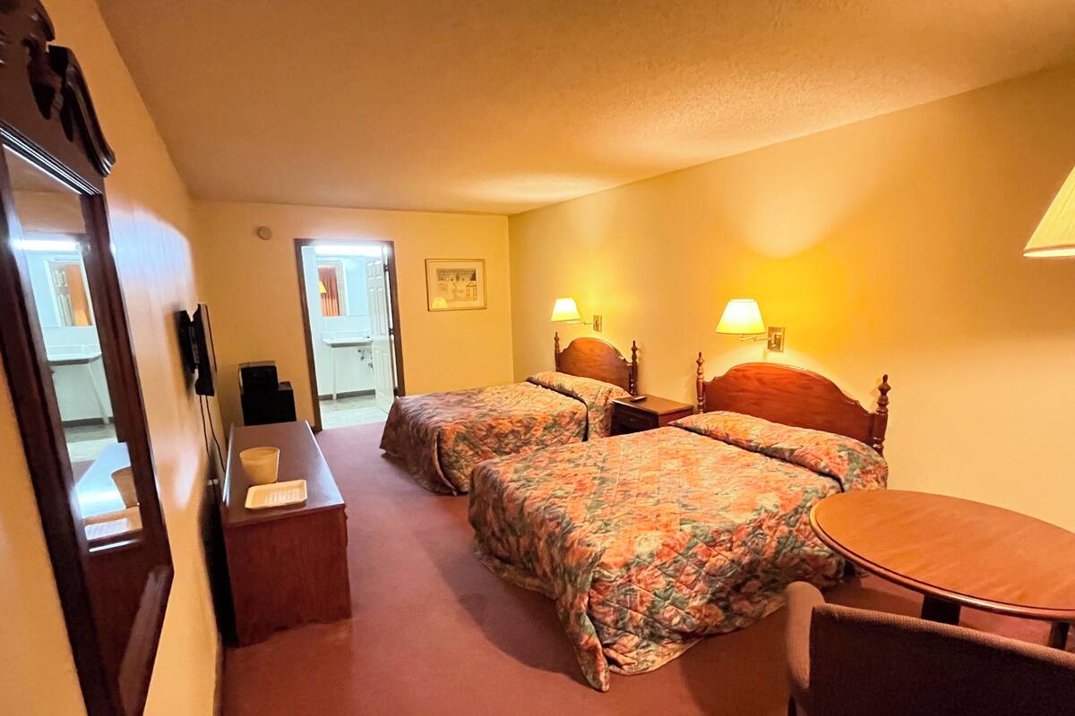 Une chambre d’hôtel avec deux lits, un bureau, une chaise et une petite table.
