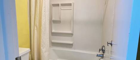 Une salle de bain comprenant des toilettes, une baignoire et une douche.