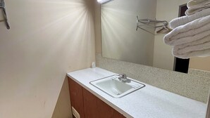 Ein Badezimmer mit Waschbecken, Spiegel, Handtuchhalter und einer Lampenleuchte.