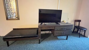 Ein Zimmer mit Schreibtisch, Fernseher, Telefon und Stuhl.