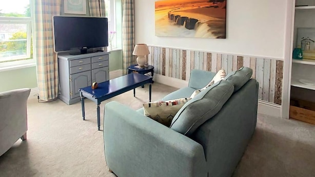 A living room with a sofa, a TV, a lamp, and a painting on the wall. - Cosy light and spacious apartment in the heart of Stratton  (Stratton)