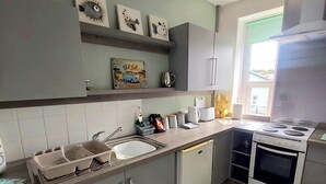 A compact kitchen with a sink, stove, and cabinets. - Cosy light and spacious apartment in the heart of Stratton  (Stratton)