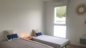 A bedroom with two single beds, a window, and a wall-mounted air conditioner. - BETWEEN PINES AND OCEANS, IDEAL FOR FRIENDS AND FAMILY (Léon)