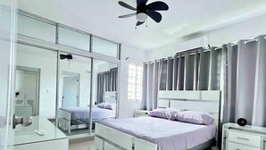 Une chambre à coucher moderne avec un lit, des tables de chevet, un miroir et un ventilateur de plafond.