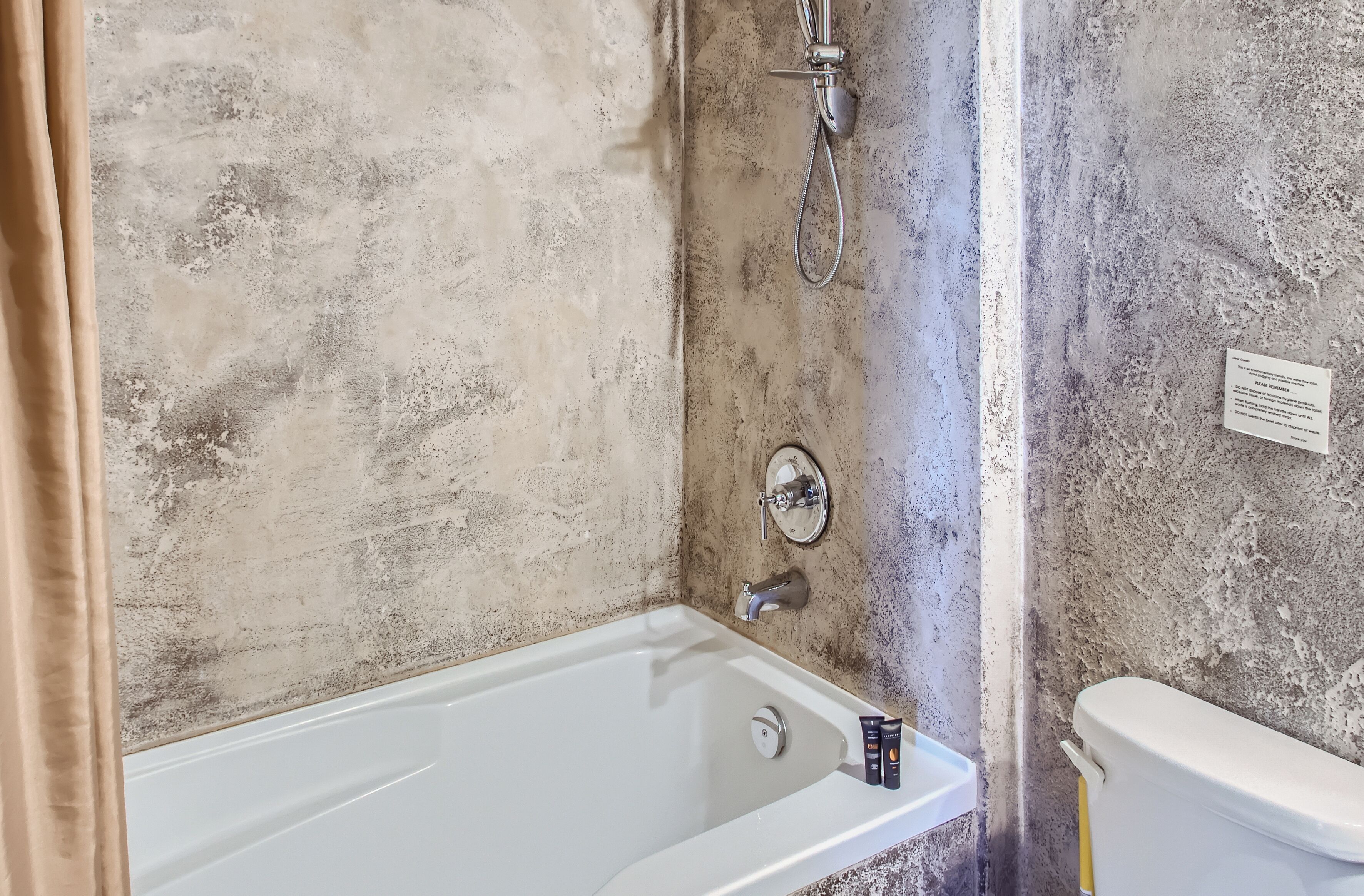 A bathroom with a bathtub, a toilet, and a shower head.
