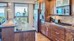 A modern kitchen with wooden cabinets, stainless steel appliances, and a large island. - The Timbers by Okanagan Premier (Beaverdell)