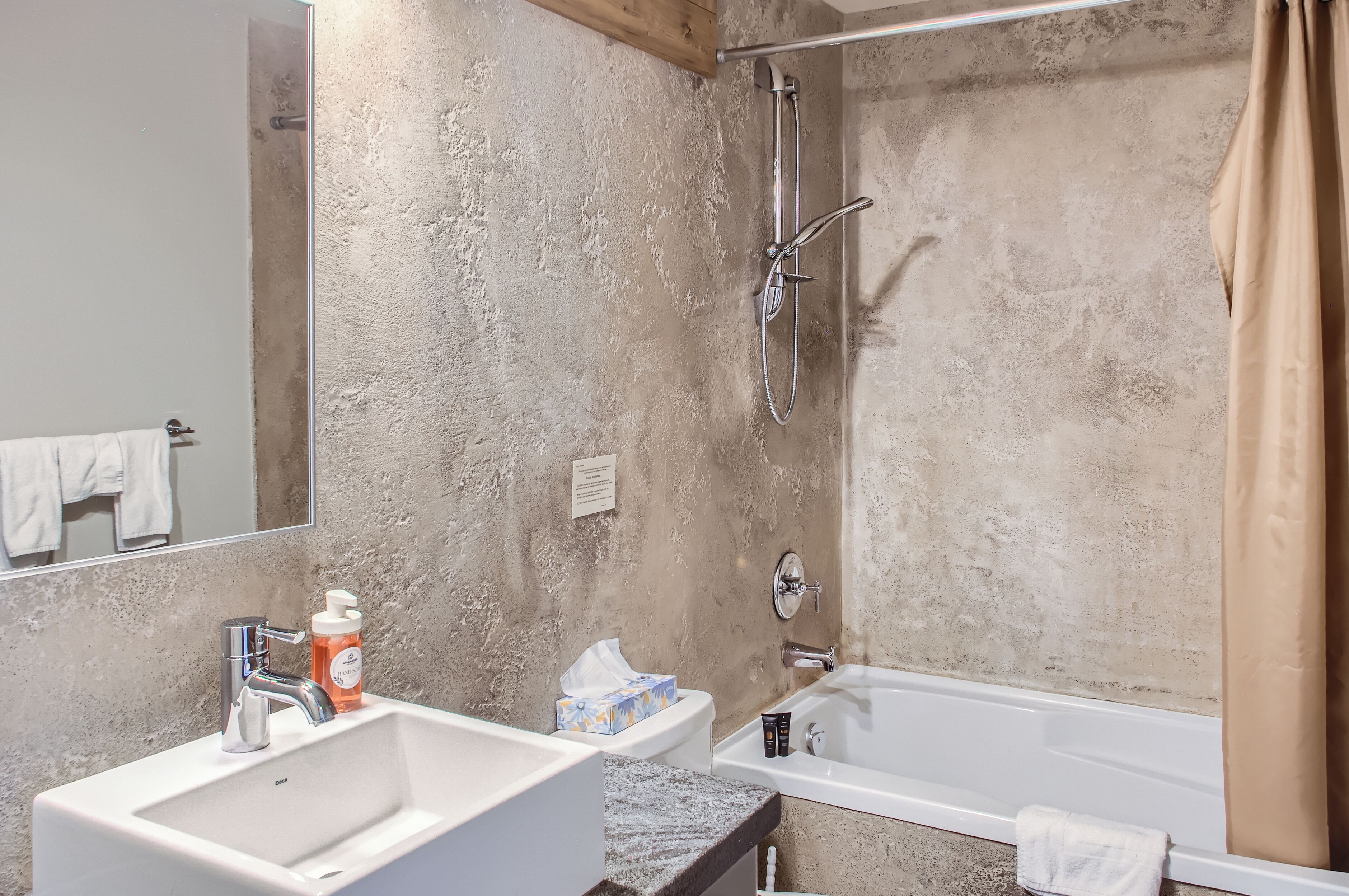 Une salle de bain avec un lavabo blanc, un miroir, une douche et une baignoire.