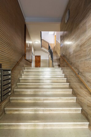 Un escalier avec une rampe en bois et des marches de couleur beige, menant à une porte située en haut.
