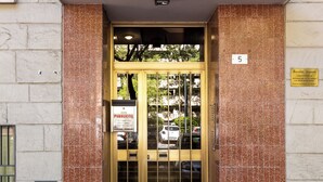 Fachada de edificio con azulejos, placa con número y señal de acceso público.
