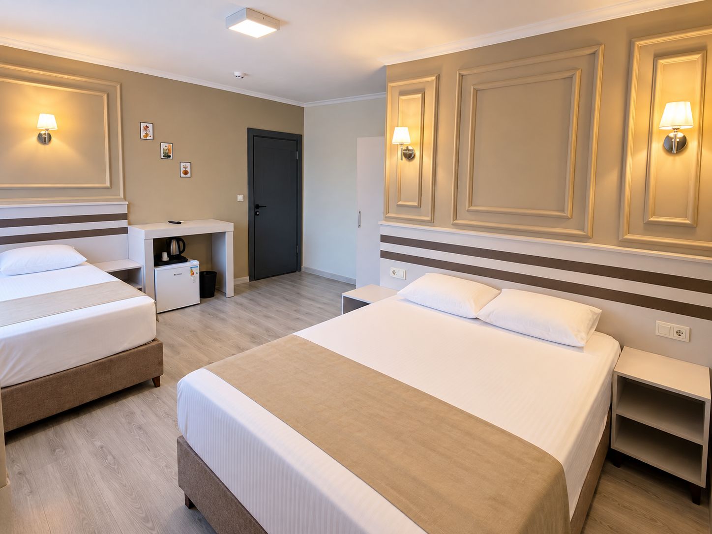 A hotel room with two beds, a desk, and a door.