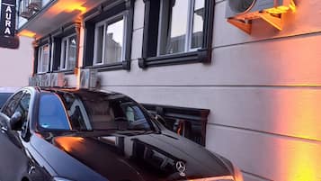 Een zwarte Mercedes-Benz geparkeerd voor een gebouw met een bord waarop 'GRAND AURA' staat.