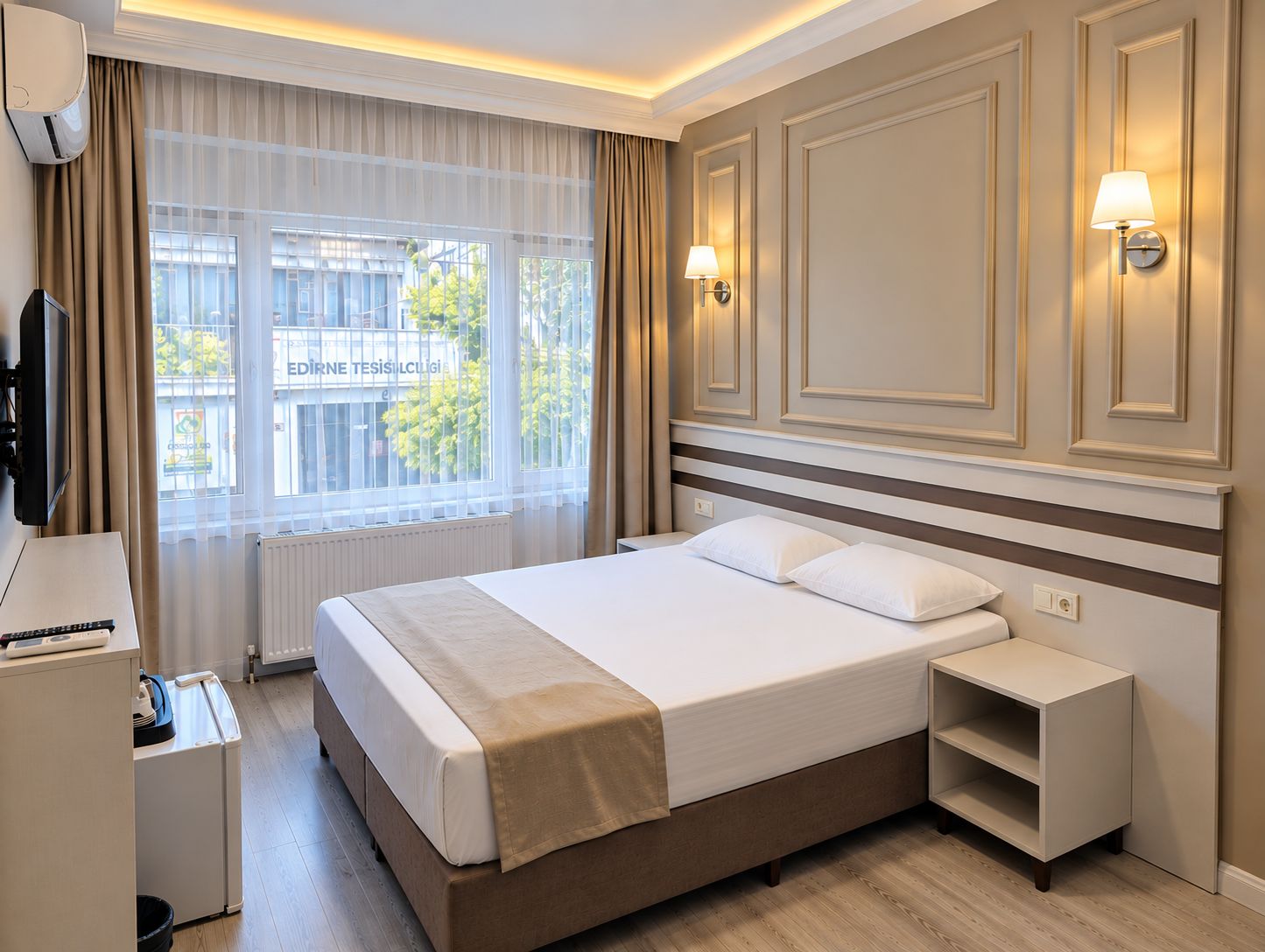 Una habitación de hotel con cama, mesitas de noche, televisión y ventana con cortinas.