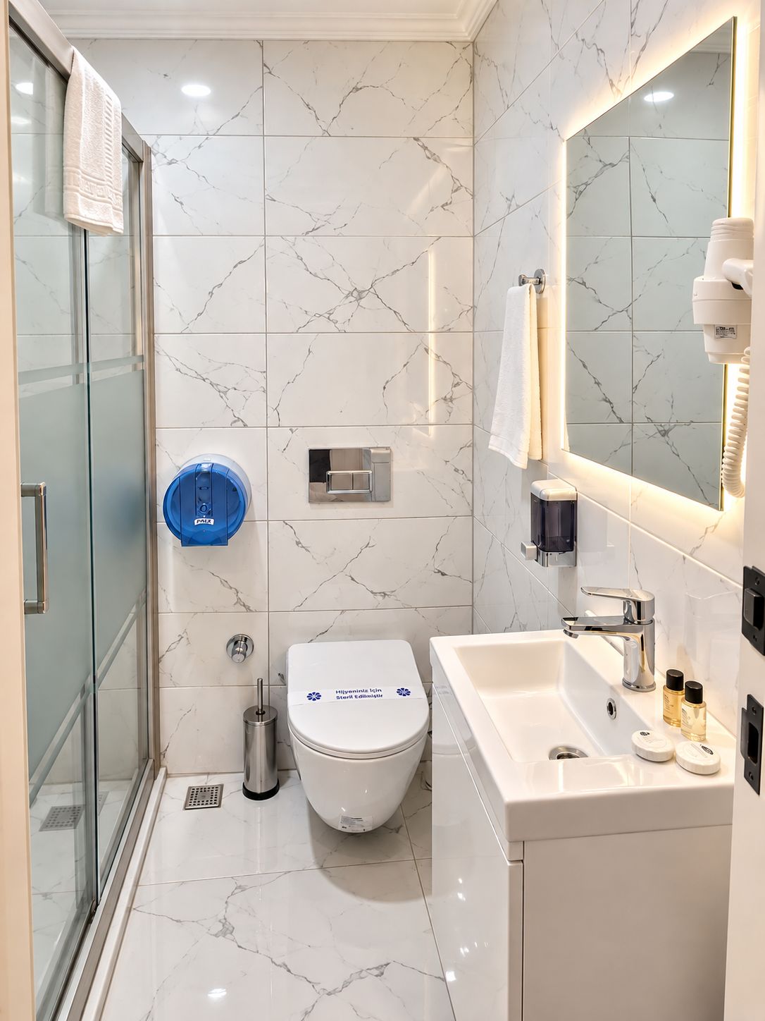 A modern bathroom with a glass shower enclosure, a white toilet, a sink with a mirror, and a towel rack.