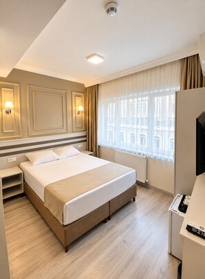 A hotel room with a large bed, bedside tables, a TV, and a window with curtains. - Grandaura Edirne (Edirne)