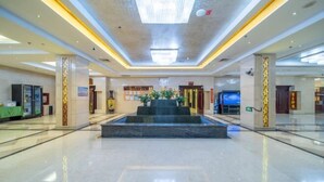 A spacious lobby with a central water feature, marble flooring, and modern lighting. - Yulong Hotel (Wusu)