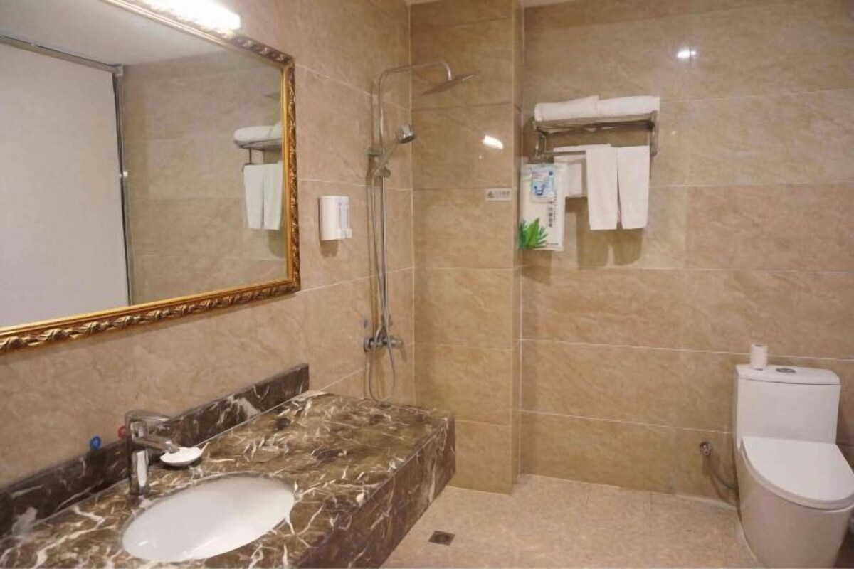 A bathroom with a marble sink, a mirror, a shower, and a toilet.