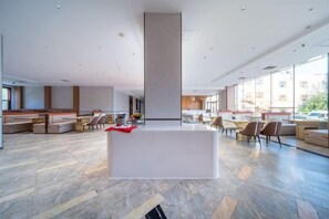 A spacious lobby with a reception desk, seating areas, and large windows. - Yulong Hotel (Wusu)
