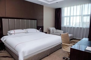 A hotel room with a large bed, a desk, a chair, and a window with curtains. - Yulong Hotel (Wusu)