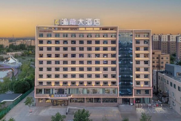 A multi-story hotel with a modern facade, featuring a prominent entrance and a parking area in front.