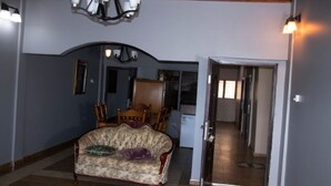 A room with a vintage sofa, a chandelier, and a dining area with chairs and a table. - Joyful Haven apartments (Nkoranza)