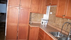 A kitchen with wooden cabinets, a granite countertop, a stainless steel sink, and a coffee maker. - Joyful Haven apartments (Nkoranza)