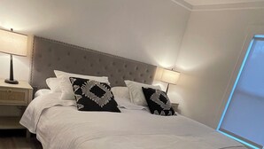 Un dormitorio con una cama grande, dos mesitas de noche y un ventilador de techo.