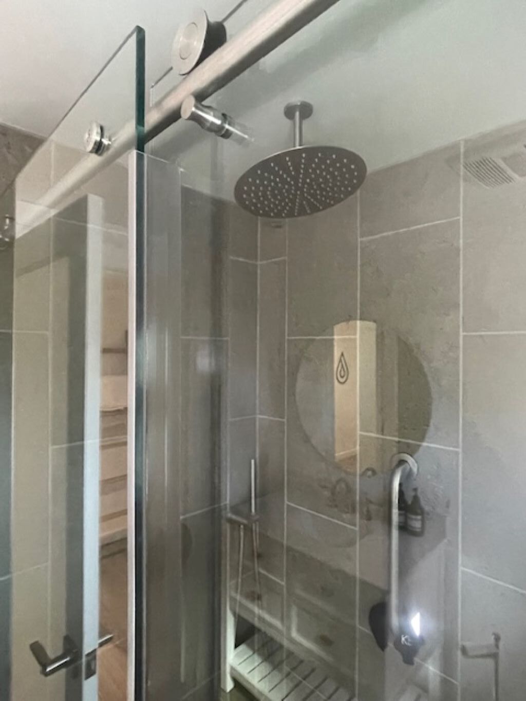 A glass-enclosed shower with a rain showerhead and a handheld showerhead.