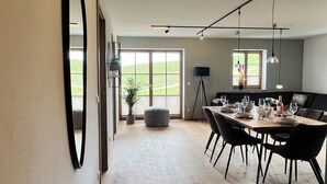 A spacious dining area with a wooden table set for six, a large mirror on the wall, and a bench in the foreground.