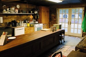 A rustic kitchen with wooden cabinets, a stove, and various kitchen appliances.