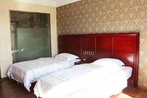 Une chambre d’hôtel avec deux lits, une tête de lit en bois, un papier peint à motifs et une porte-fenêtre coulissante.