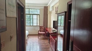 Una habitación con una cama, un escritorio, una silla, un televisor y una ventana con cortinas.