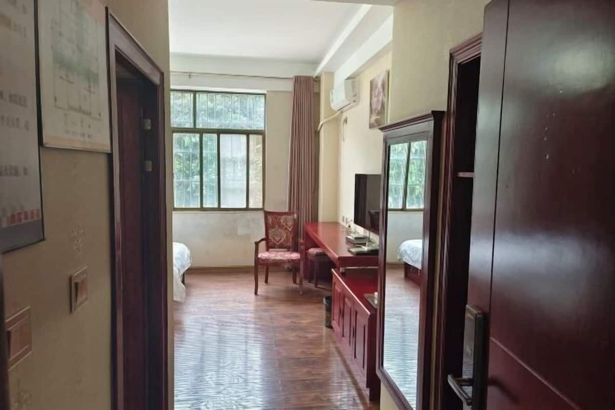 Una habitación con una cama, un escritorio, una silla, un televisor y una ventana con cortinas.