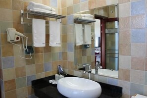 Ein Badezimmer mit Waschbecken, Spiegel, Handtuchhalter und einem Föhn.