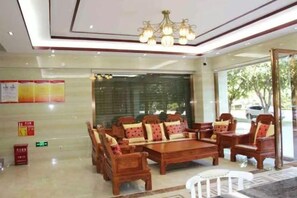 Un hall de hotel con un conjunto de sofá de madera, una silla blanca y una araña.