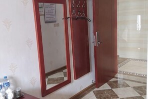 Une pièce avec une porte rouge, un miroir et un sol carrelé.