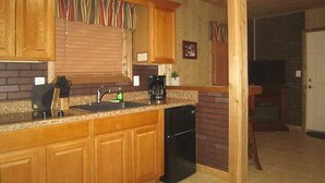 A kitchen with wooden cabinets, a sink, and a black dishwasher.