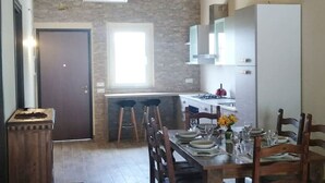 A modern kitchen with a central island, a dining area with a table set for four, and a large window providing natural light.