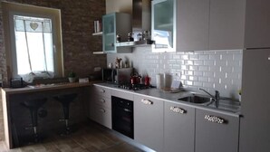 A modern kitchen with grey cabinets, a built-in oven, and a window with a heart-shaped decoration.