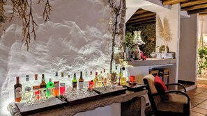 A bar area with a variety of liquor bottles and glasses, a stone counter, and a seating area with chairs. - CASAL DA SERRANA  - Rural Tourism - Between Óbidos & Peniche (Reguengo Grande - Lourinha)