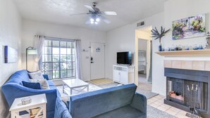 Una sala de estar con un sofá azul, un televisor, una chimenea y un cuadro en la pared.