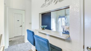 Un interior moderno con una puerta blanca, un sillón azul y un espejo con un adorno en la pared.